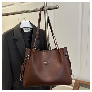 Detail of a large brown faux leather tote bag with silver ring and side strap accent