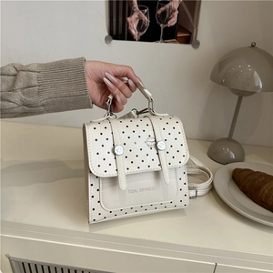 Chic white polka dot handbag with top handle and adjustable strap for women