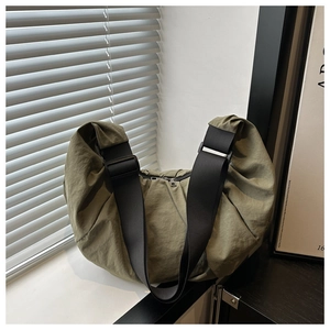 Close-up of olive green crossbody bag featuring pleated nylon texture and black wide strap