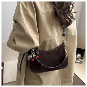 Détail du sac demi-lune en daim marron foncé avec breloque cerise et chaîne dorée