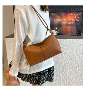 Detail of a brown leather shoulder bag featuring unique knotted strap and gold hardware