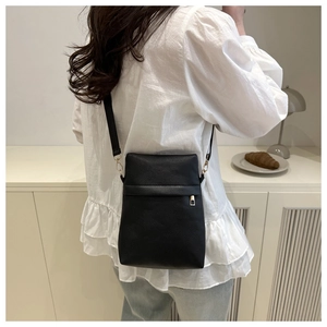 Detail showing back view of black lychee texture crossbody bag with adjustable strap