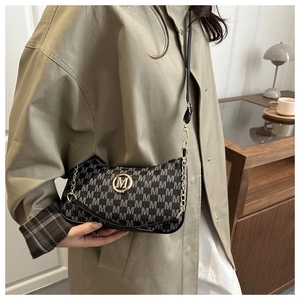 Detail showing monogram M print texture and golden metal logo on chic small square bag
