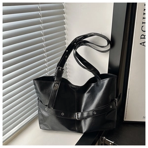 Detailed view of black faux leather tote with metallic buckles and belt decorations