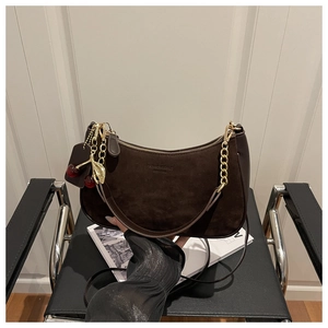 Détail du sac hobo en daim marron foncé avec gaufrage et pendentif cerise élégant