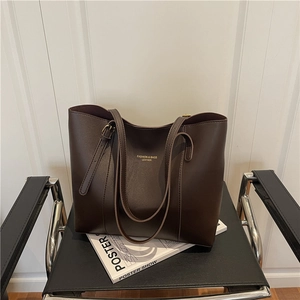 Large dark brown leather tote bag with adjustable straps and gold foil lettering logo