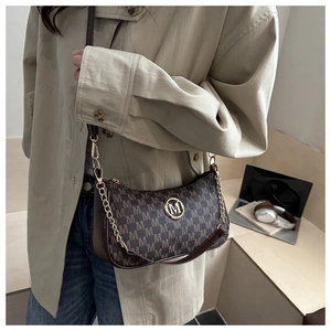Détail de l'imprimé monogramme M et du logo en métal doré sur un sac demi-lune marron