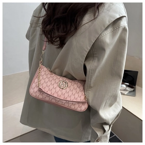 Detailed view of pink shoulder bag featuring letter patterns and gold metal logo charm