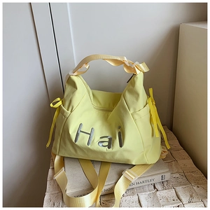 Detail of yellow nylon tote bag with Hai embroidery and stylish bow accents on side