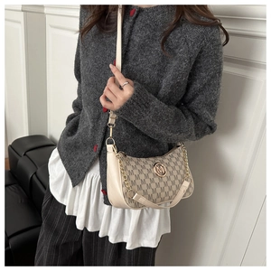 Detail of beige monogram shoulder bag with metal M logo and stylish chain strap on model