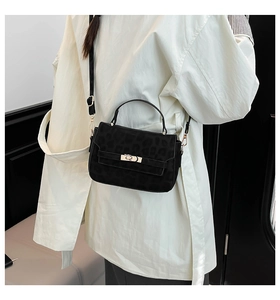 Detail of black leopard embossed crossbody bag with gold metal buckle and suede texture