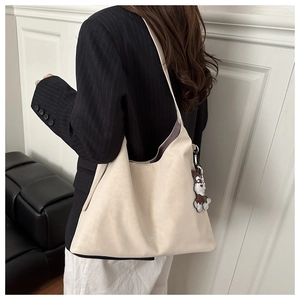 Close-up of off-white faux suede tote bag with cute dog charm on a model