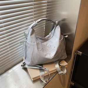 Blue-grey nylon tote bag with Michigan embroidery and side drawstring detail in soft light