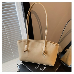 Macro detail of creamy beige tote bag featuring knotted straps and golden metal hardware