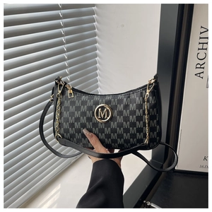 Détail du sac croissant noir avec imprimé monogramme et logo M en métal doré
