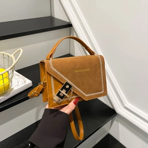 Brown vintage leather crossbody bag with metal lock and V-stitch detail on stairs