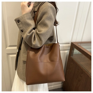 Brown leather tote bag featuring contrast stitching and large capacity shown on a model