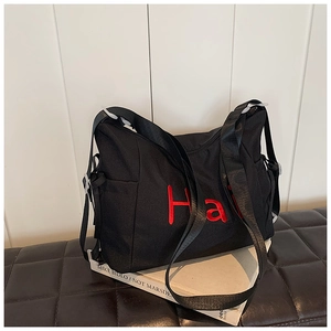 Detail of black nylon tote bag featuring red embroidered Hali letters and side pocket