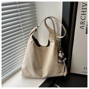 Detail of off-white suede tote bag with cute plush dog pendant and spacious interior