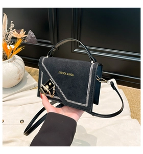 Detail of black suede textured bag featuring white V-shape stitching and gold hardware