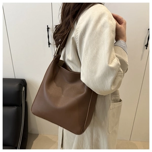 Detail view of the deep brown leather bucket bag with wide strap and matte finish