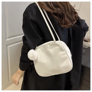 Close-up of white PU leather shoulder bag featuring a decorative plush fur ball charm