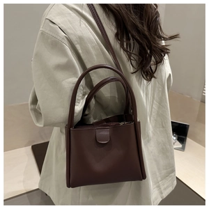 Detail view of dark brown leather bucket bag with top handles and zipper closure