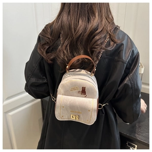 Détail d'un mini sac à dos avec imprimé chat, chaîne dorée et bretelles en cuir