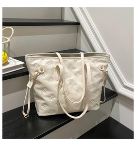 Detail of embossed bow texture and golden metal hardware on cream white tote bag