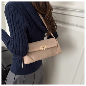 Detail of minimalist beige flap bag featuring a golden circular ring lock and mixed textures