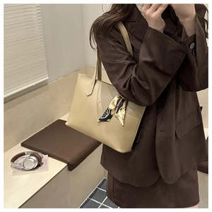Detail of beige leather tote bag featuring a decorative silk scarf and contrast stitching