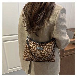 Close-up of leopard print tote bag featuring black leather trim and fashion label