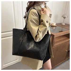 Detail view of large black tote bag with woven texture on model for daily commuting