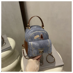 Détail du mini sac à dos en denim bleu avec broderie chat noir et poignée en cuir