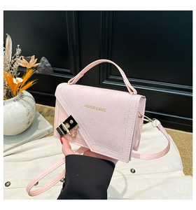 Detail of pink fashion bag featuring a geometric flap with a gold buckle and fine stitching