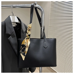 Detail of black leather tote bag with silk scarf and white contrast stitching detail