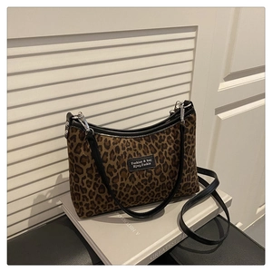 Close-up of leopard print tote bag texture with black shoulder strap and leather detail