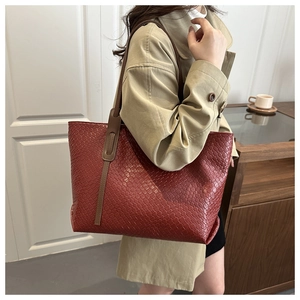 Detail of burgundy woven tote bag showing diamond texture and brown leather straps