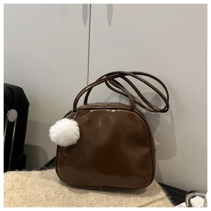 Detailed view of dark brown vintage handbag with polished leather and plush ball charm
