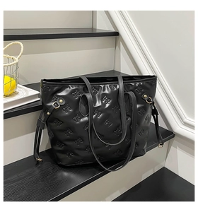 Detail of black tote bag with embossed bow patterns and golden metal buckle hardware