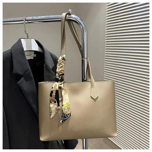 Detail of beige faux leather tote bag with vintage scarf handle on a metal hanger