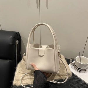 Minimalist beige PU leather bucket bag with inner pouch on a cozy sofa background