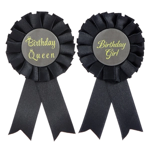 Macro shot of black satin Birthday Queen and Birthday Girl badges with pleated edges