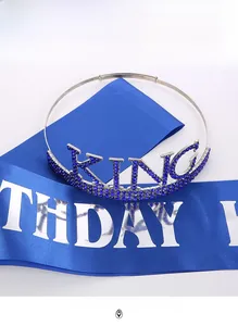 Close-up of a silver King crown with blue rhinestones and a blue Birthday sash