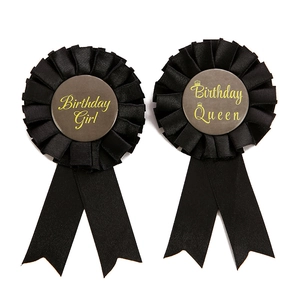 Detail view of Birthday Girl and Birthday Queen tinplate badges with black satin ribbons