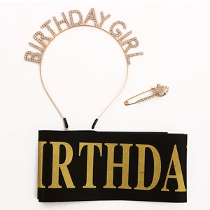 Detail shot of golden rhinestone Birthday Girl headband, satin sash, and crown safety pin
