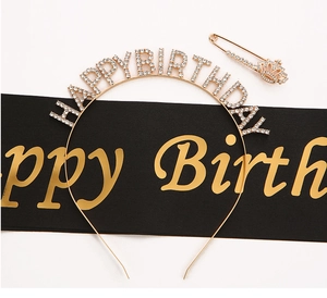 Detail of gold rhinestone Happy Birthday headband with black satin sash and crown pin