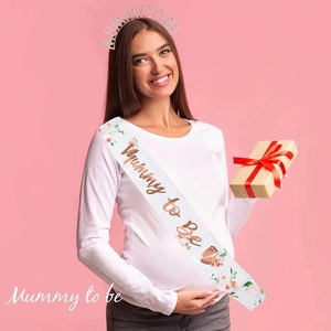 Detail of silver rhinestone Mummy To Be tiara and floral satin sash on a pregnant model