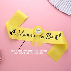 Close-up of yellow Mommy to Be sash with black lettering and footprint for baby showers