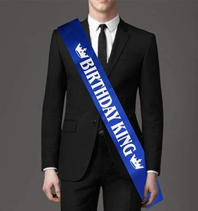 Detail of blue satin Birthday King sash with white lettering and crown icons for men